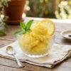 Homemade lemon sherbet served in a chilled bowl with lemon slices and mint leaves